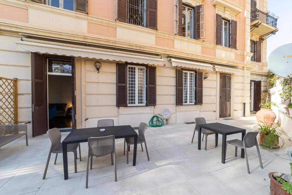 un patio con mesas negras y sillas frente a un edificio en Domus Aurea B&B and Suites, en Roma