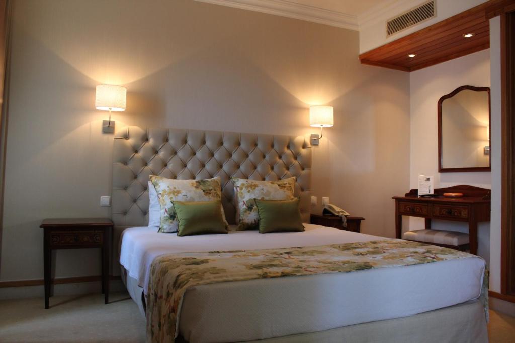 a bedroom with a large bed with a large headboard at Hotel Solar Palmeiras in Paço de Arcos