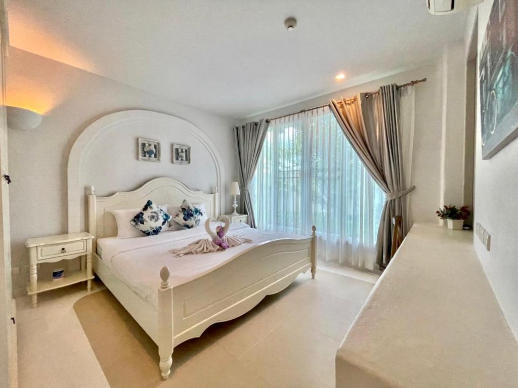 1 dormitorio con cama blanca y ventana grande en Chelona huahin beachfront resort condo, en Khao Tao