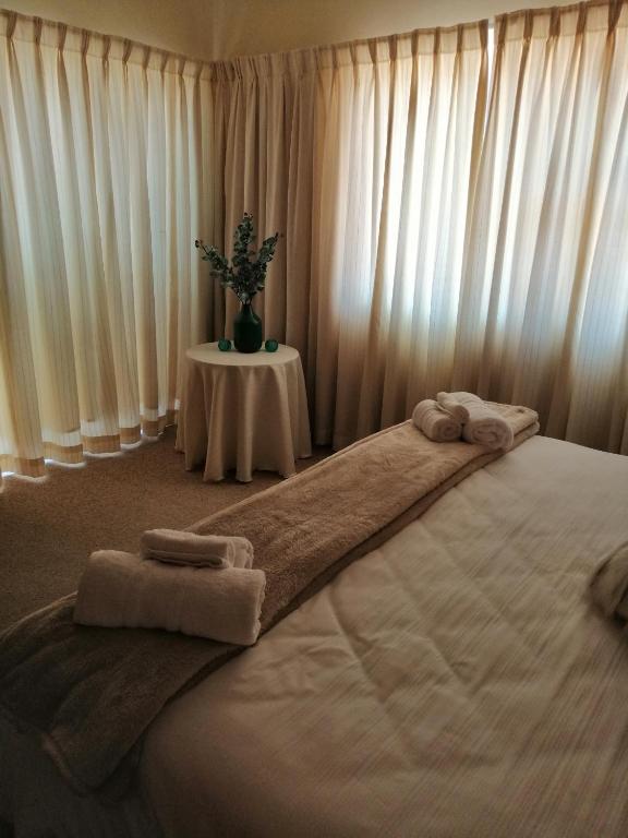 a bedroom with a large bed with towels on it at Villa Monique Self Catering Apartment in Sedgefield