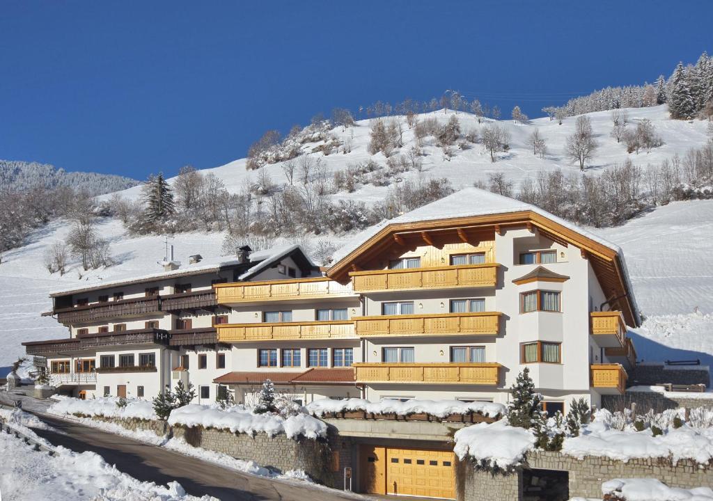 un grande edificio nella neve con una montagna di Hotel Onach a San Lorenzo di Sebato