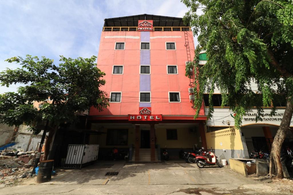 een roze hotel met een motorfiets er voor geparkeerd bij AMS Hotel Koja in Jakarta
