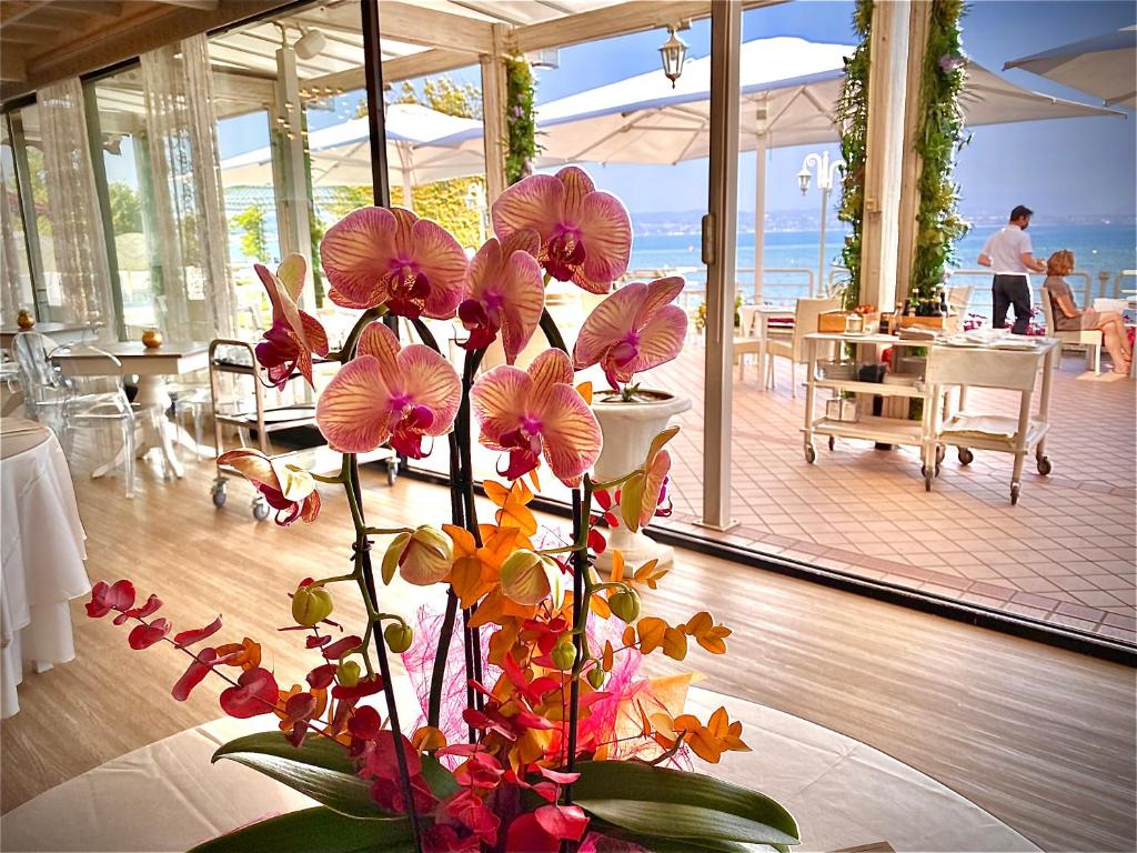 wazon wypełniony kwiatami na stole w restauracji w obiekcie Hotel Aquila D'Oro Desenzano w mieście Desenzano del Garda