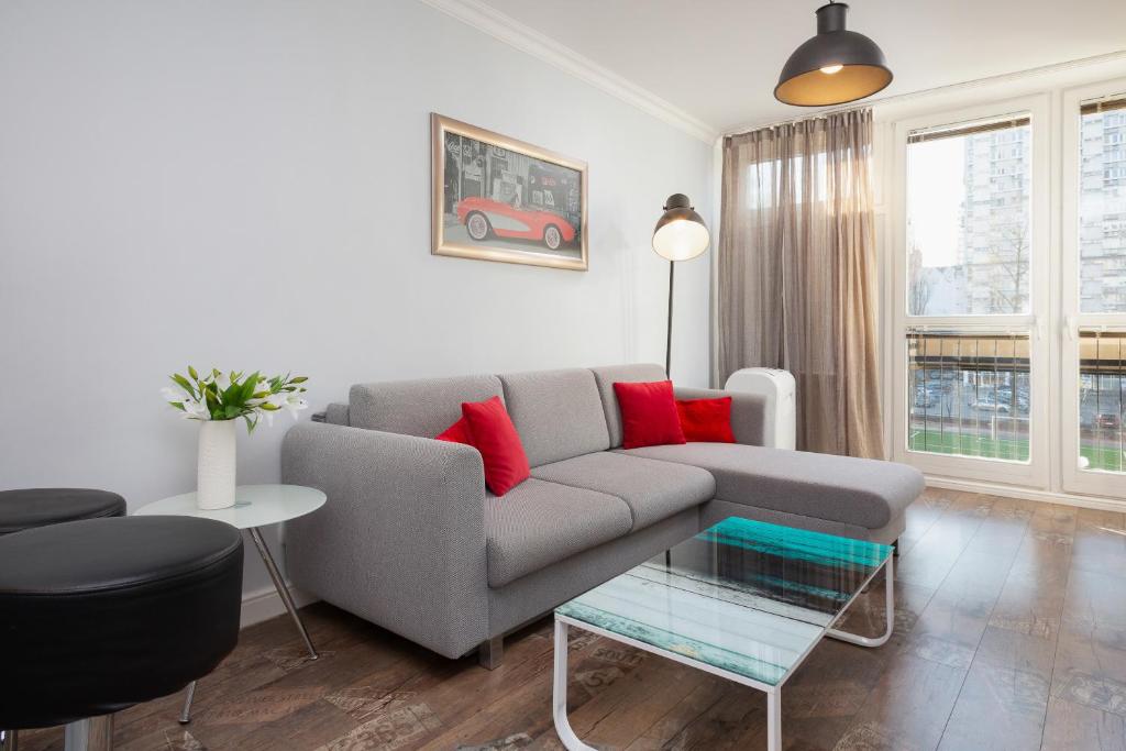 華沙的住宿－Warsaw Apartament Rondo ONZ，客厅配有灰色沙发和红色枕头