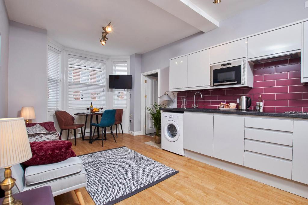 uma cozinha e sala de estar com uma parede com detalhes em roxo em Delven House- Serviced Apartments em Castle Donington