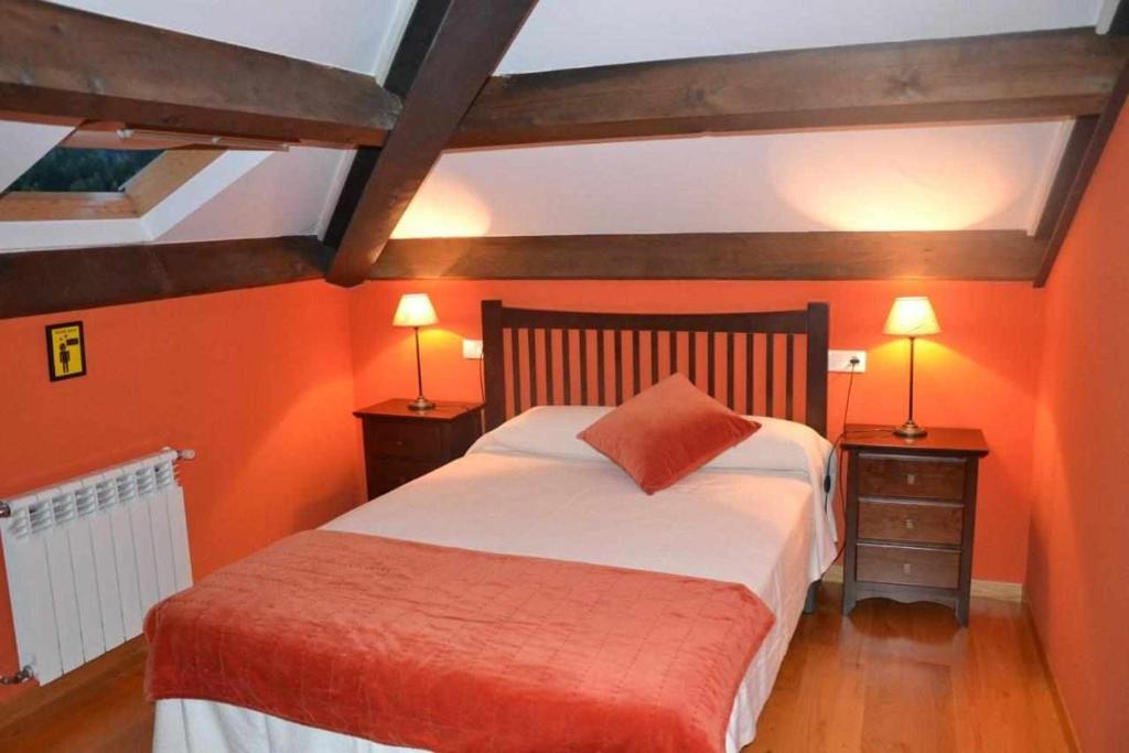 um quarto com paredes cor-de-laranja e uma cama com 2 candeeiros. em Apartamento La Casa del Abuelo Justo em Miñagón