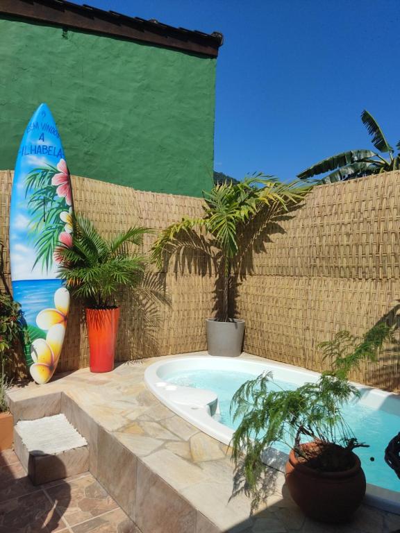a bath tub sitting next to a wall with a surfboard at Recanto Toca das Plantas de Ilhabela I in Ilhabela
