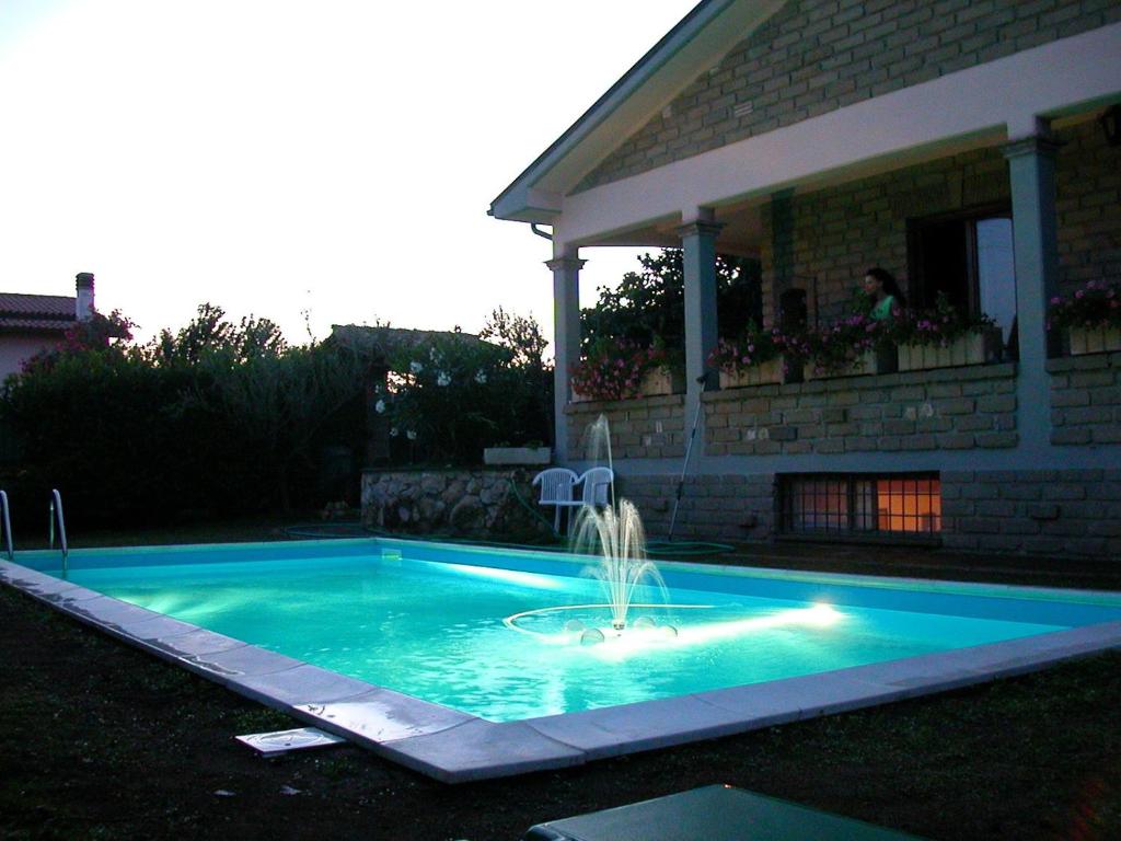 a swimming pool with a fountain in front of a house at Villa Giuliana in Anguillara Sabazia