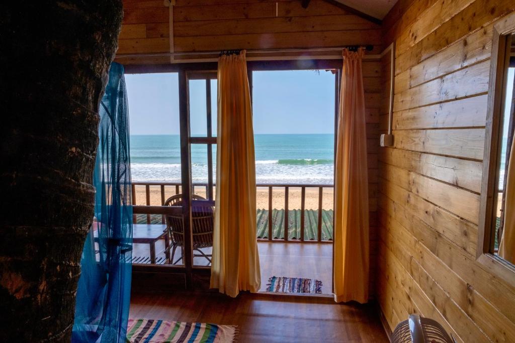 a room with a balcony with a view of the ocean at Jardim a Mar in Agonda