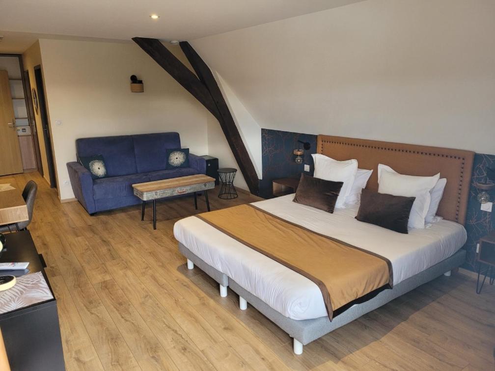 een slaapkamer met een groot bed en een blauwe bank bij Les chambres de la Cotinière - Bord de Saône - St Jean de Losne in Saint-Jean-de-Losne