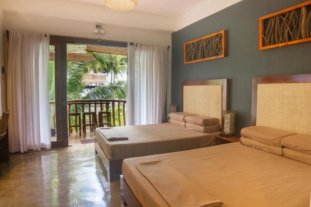 a bedroom with two beds and a balcony at Lagkaw Siargao Villas in General Luna