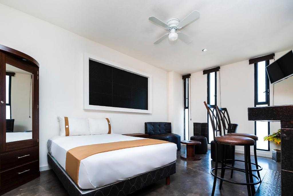 a bedroom with a bed and a ceiling fan at Capital O Hotel Joyma Suites, San Luis in San Luis Potosí