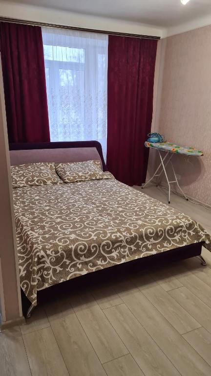 uma cama num quarto com cortinas vermelhas em Квартира 1-кімнатна в центрі Миргорода. em Myrhorod