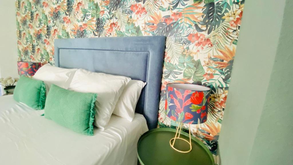 Cama con cabecero azul con almohadas y mesa en Loft Playa Suite Málaga, en Málaga