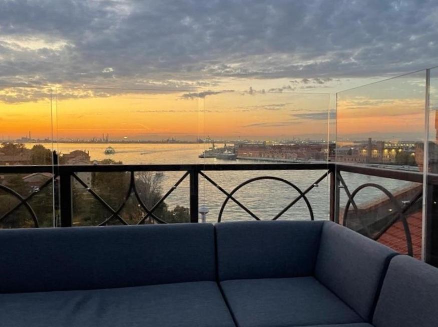 un sofá en un balcón con vistas al agua en The Venice Penthouse and Rooftop-Terrace at Molino Stucky en Venecia