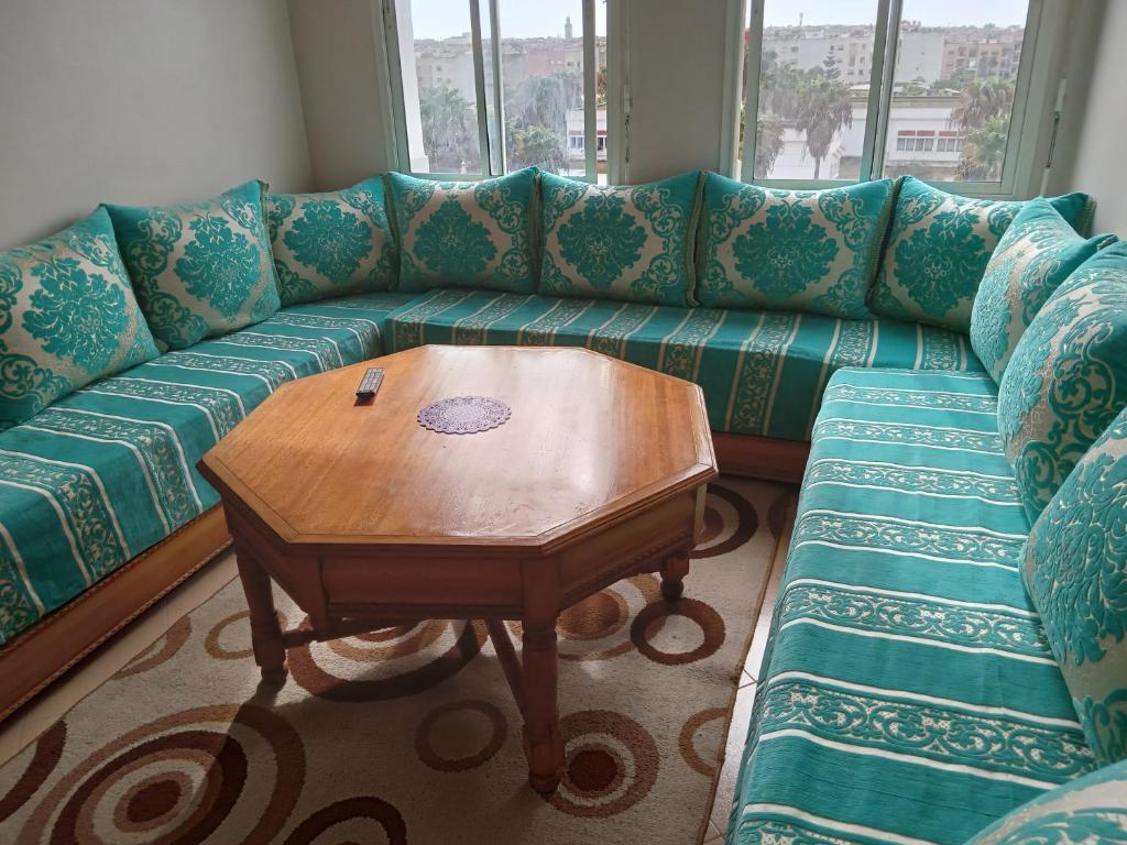 Appartement près de casanearshore et l'OFPPT في الدار البيضاء: غرفة معيشة مع أريكة خضراء مع طاولة خشبية