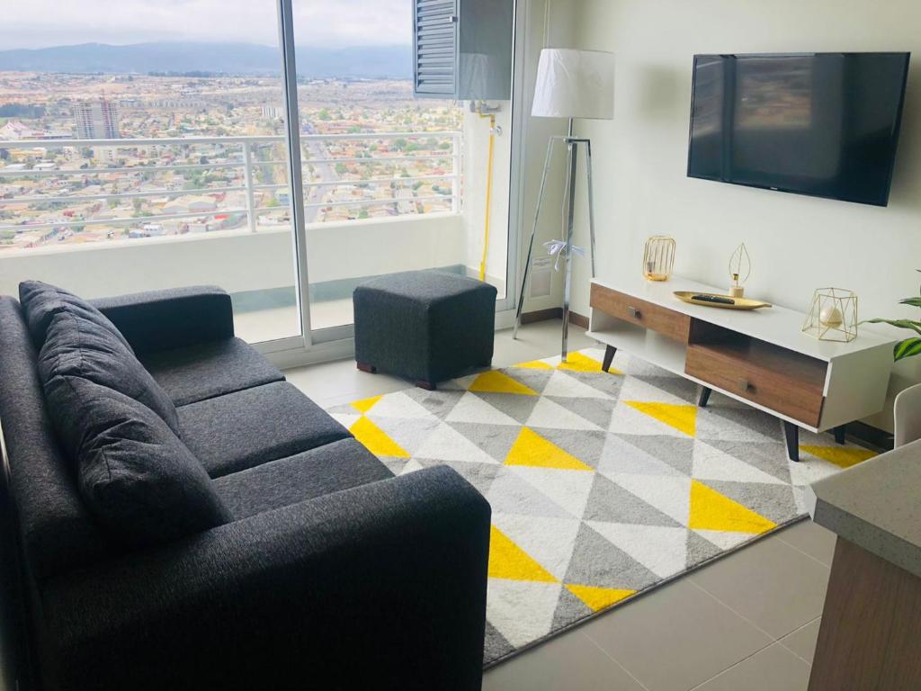 a living room with a couch and a large window at Departamento Familiar con vista al Mar in Coquimbo