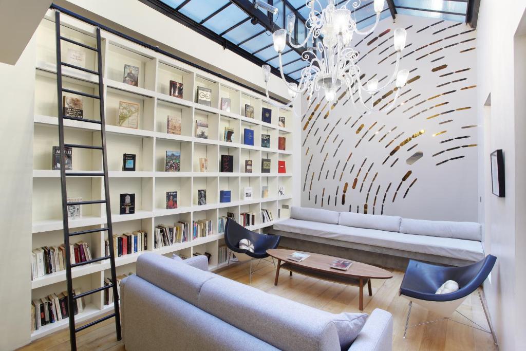 ein Wohnzimmer mit einem Sofa, Stühlen und Bücherregalen in der Unterkunft Loft center of Paris by Studio prestige in Paris