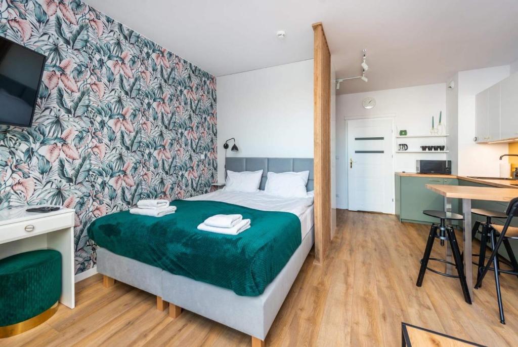 a bedroom with a bed with a green blanket at Apartament KASHMIR in Gdańsk