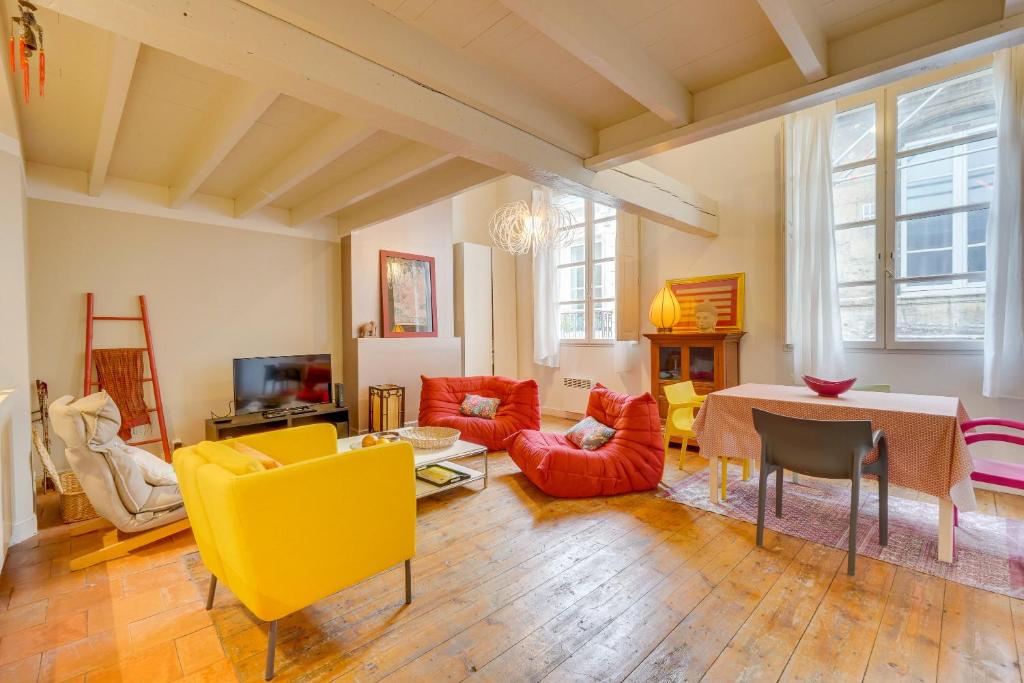 un salon avec des chaises jaune et orange et une table dans l'établissement Observance 2 bedroom duplex apartment, à Bordeaux