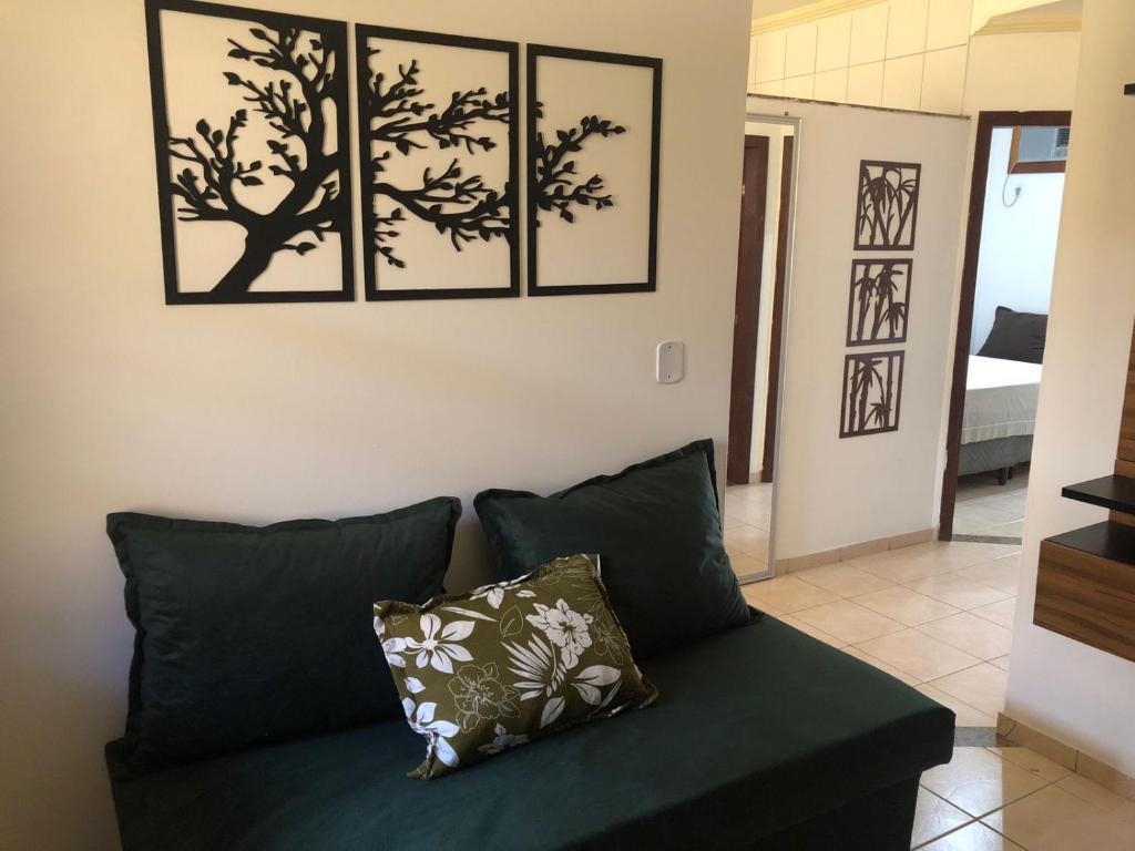 a green couch in a living room with four pictures on the wall at Jo´s Apartment in Porto Seguro