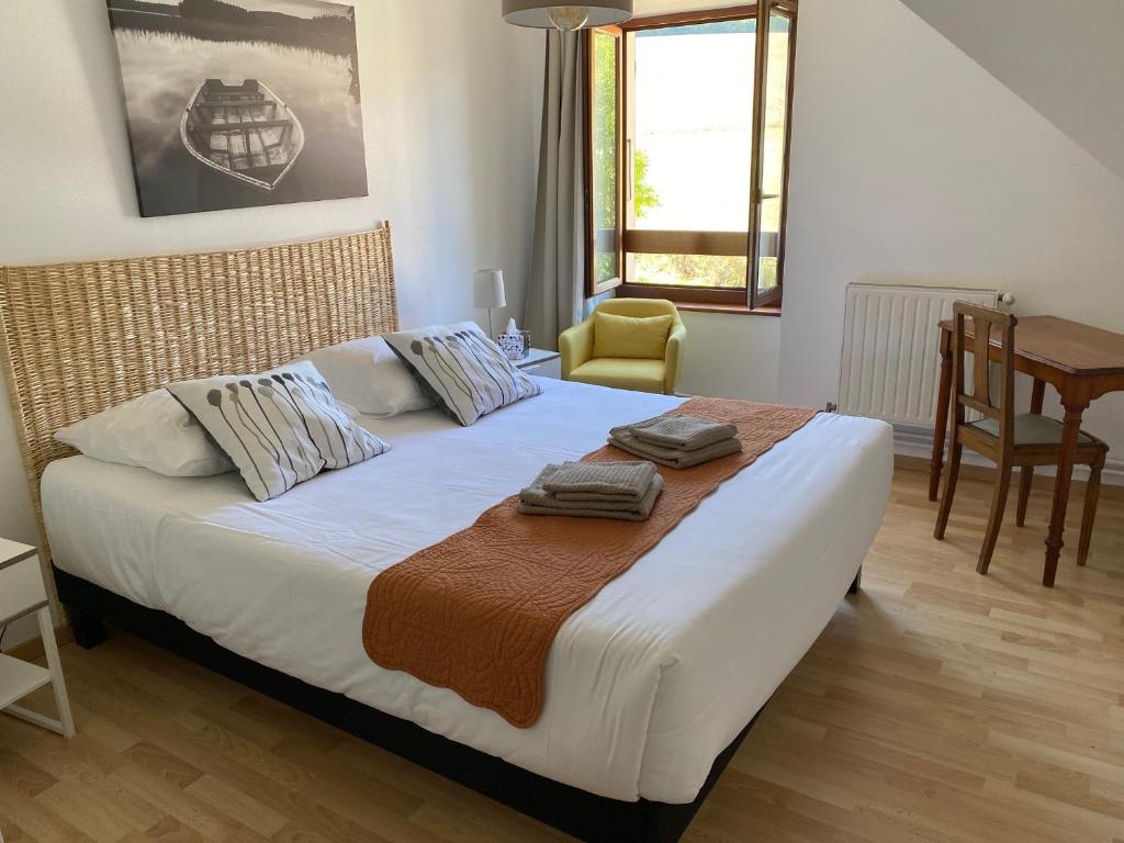a bedroom with a large bed with a chair and a table at Auberge du Grand Champ in Lalley