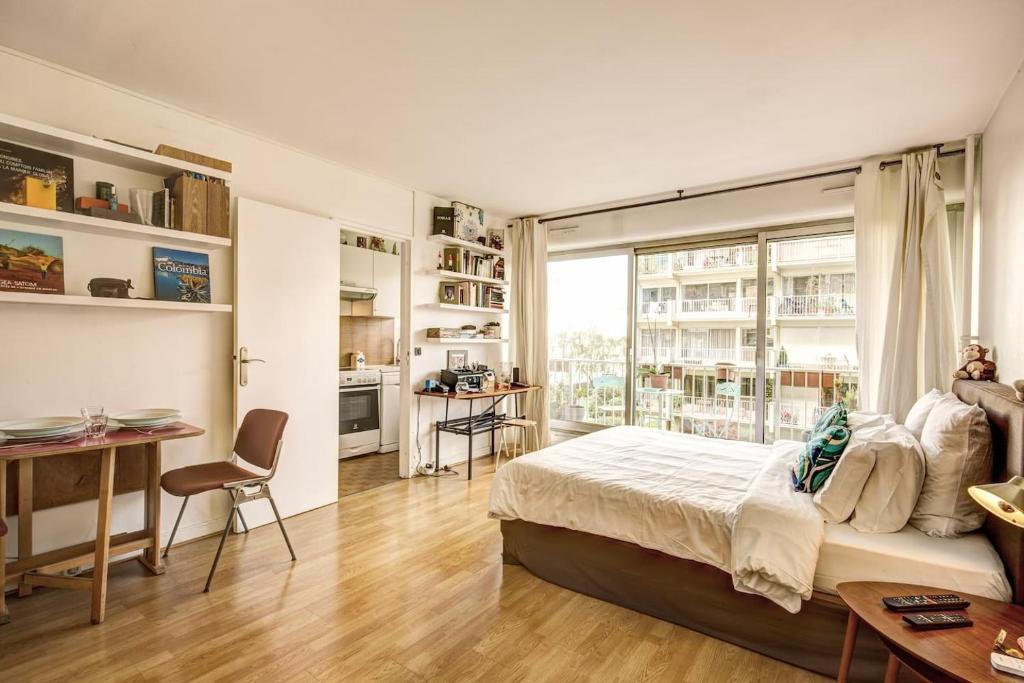 une chambre avec un lit et une grande fenêtre dans l'établissement Rue Saint-Maur 1-Bed Studio Balcony and View, à Paris