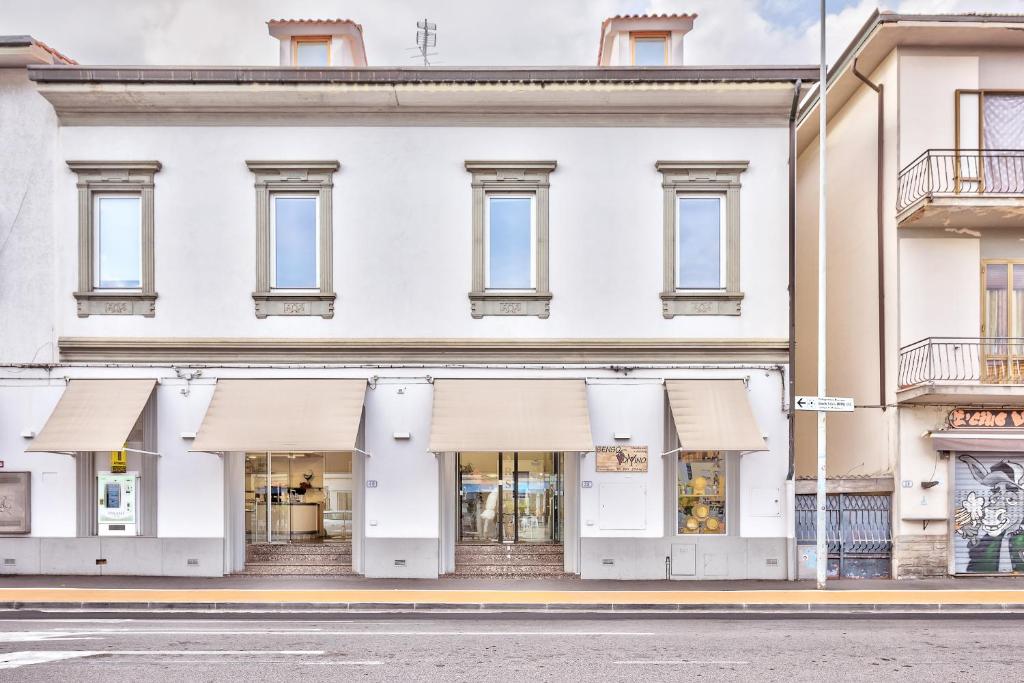 um edifício branco com toldos brancos numa rua em Affittacamere il Puntone em Empoli
