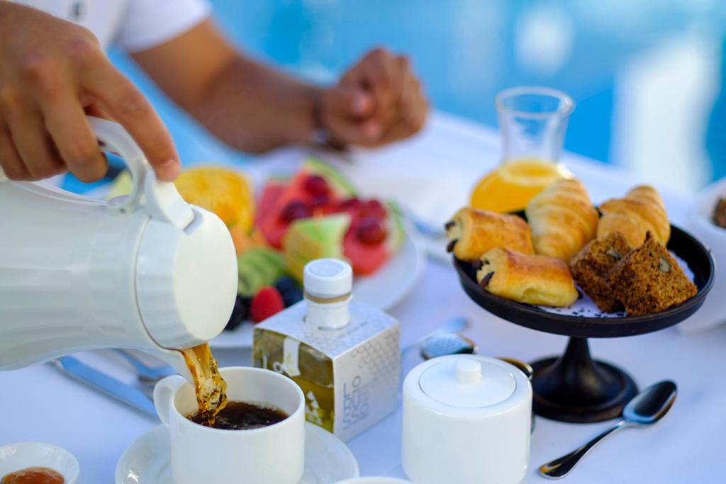a person pouring coffee into a cup on a table with a plate of food at miKasa Agua Amarga & SPA in Agua Amarga