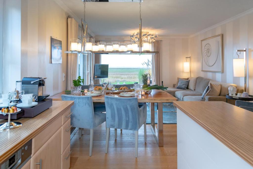 cocina y sala de estar con mesa y sillas en Ferienwohnung Luxus mit Wattenmeerblick, en Morsum