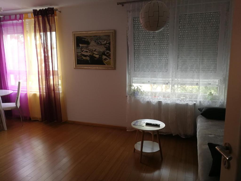 uma sala de estar com um sofá, uma mesa e uma janela em Iver apartman em Sesvete