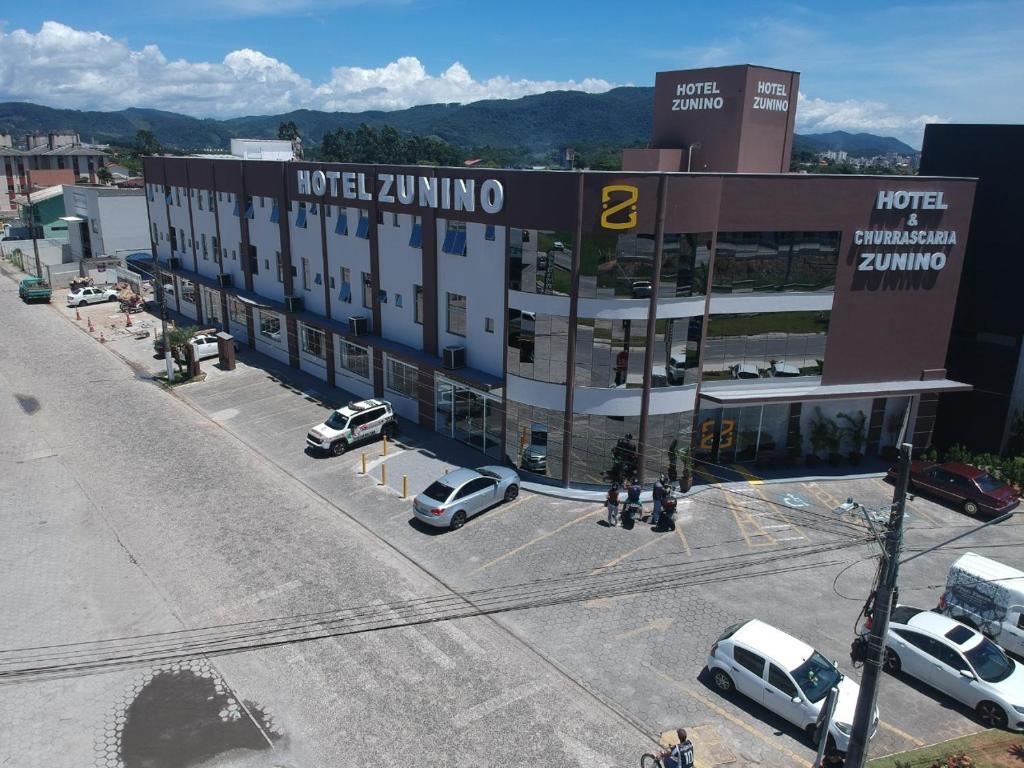 a large building with cars parked in a parking lot at Hotel Zunino in Palhoça