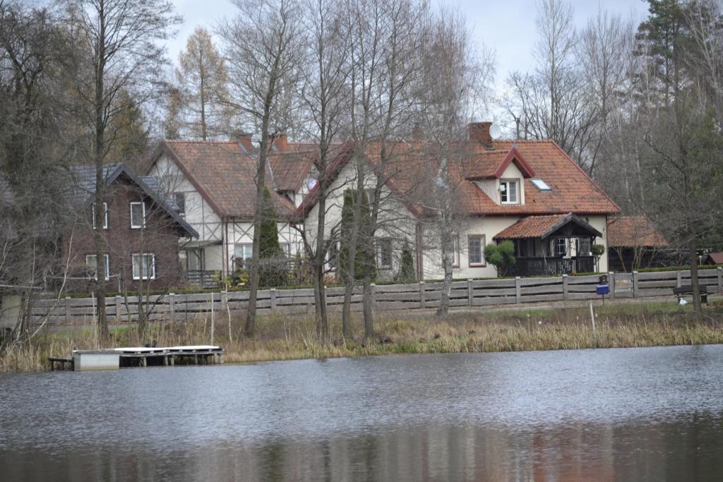 uma casa com uma cerca ao lado de uma massa de água em Willa Stodoła em Milomlyn