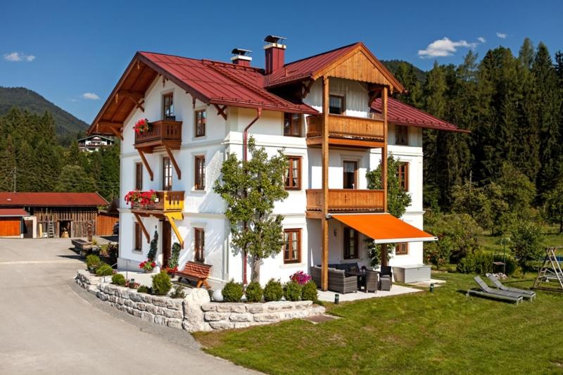 uma grande casa branca com um telhado vermelho em Haus Benzmühle em Reit im Winkl