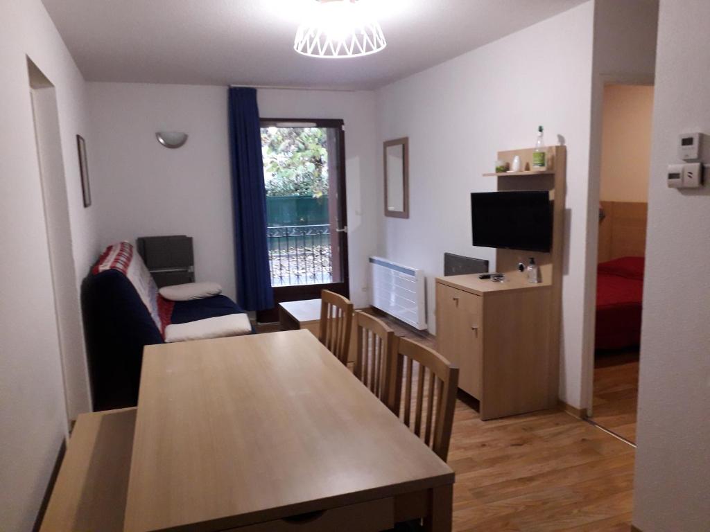 a living room with a table and chairs and a television at LES JARDINS DE RAMEL in Luchon