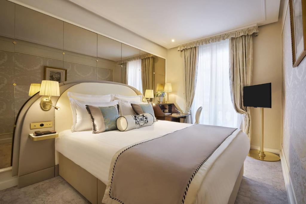 a hotel room with two beds and a mirror at Hotel Westminster in Paris