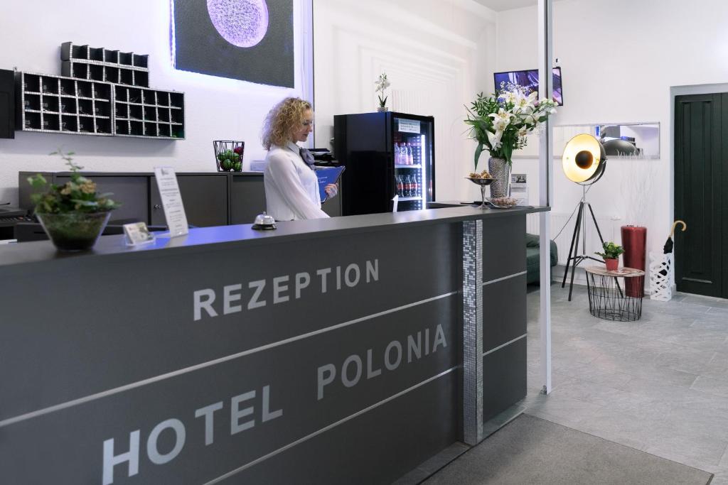 a woman is standing at a hotel reception desk at Hotel Polonia - Frankfurt&#47;Oder in Frankfurt Oder