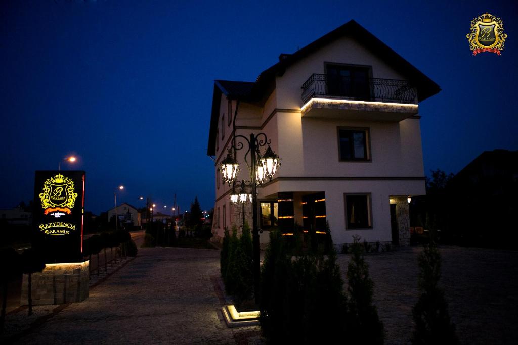 ein weißes Gebäude mit einem Schild in der Nacht davor in der Unterkunft Rezydencja Bakamus in Sandomierz