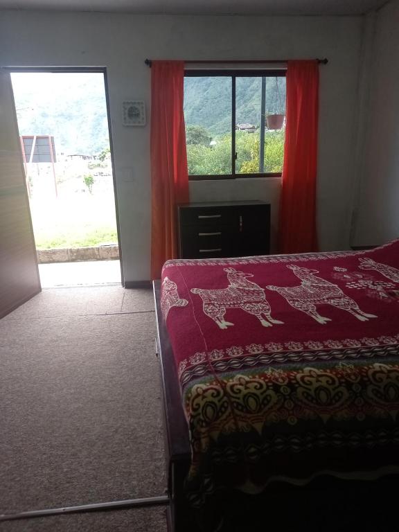 a bedroom with a bed and a window with red curtains at Montano Camping & Hostel in Baños