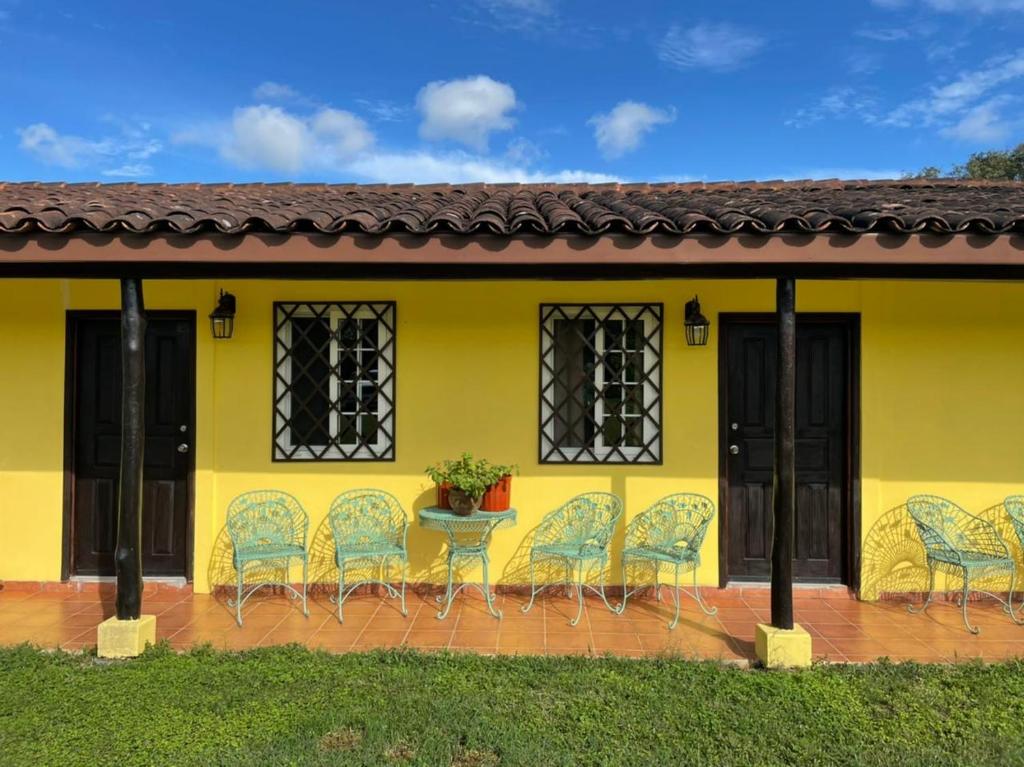 a group of chairs sitting outside of a yellow house at Finca Libelulas in Pedasí Town