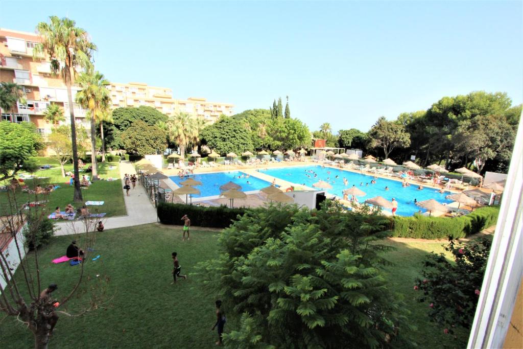 a large swimming pool with people in a park at 814 Ágata Apartamentos - VISTA AL MAR - Piscina y Playa - Excelente conexión wifi in Benalmádena
