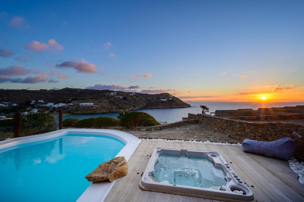 a swimming pool with a sunset in the background at Beyond Beachfront Super Paradise Villa in Mikonos