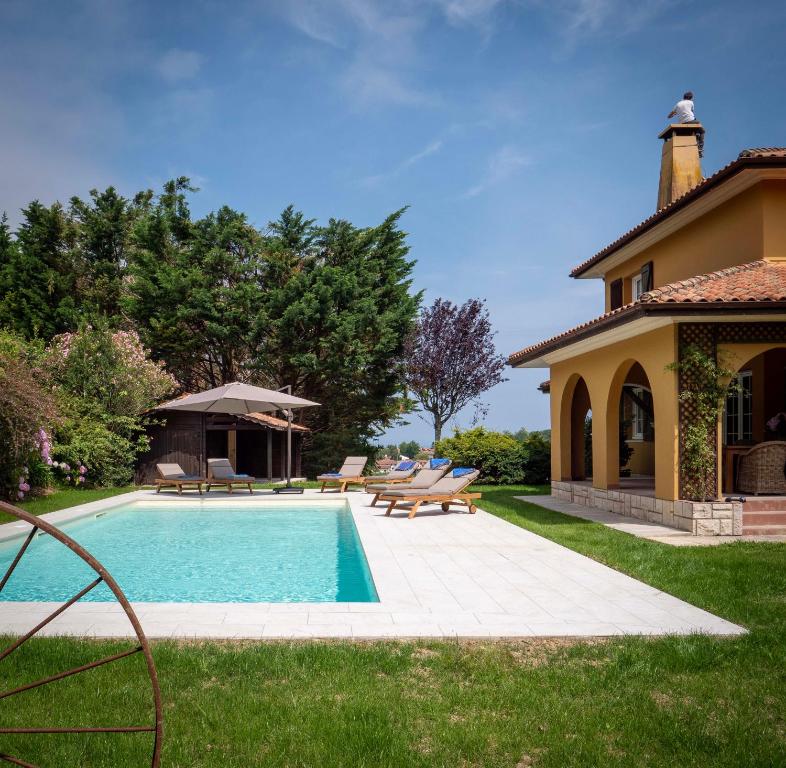 un patio trasero con piscina y una casa en Villa Enara, en Hendaya
