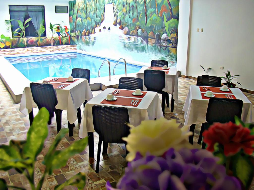 a restaurant with tables and chairs and a swimming pool at Residencial Lago Verde in Tarapoto