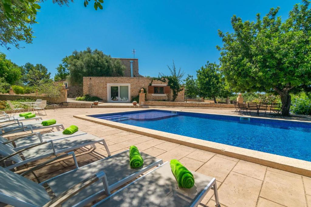 a swimming pool with lounge chairs next to a house at Saran in Llucmajor