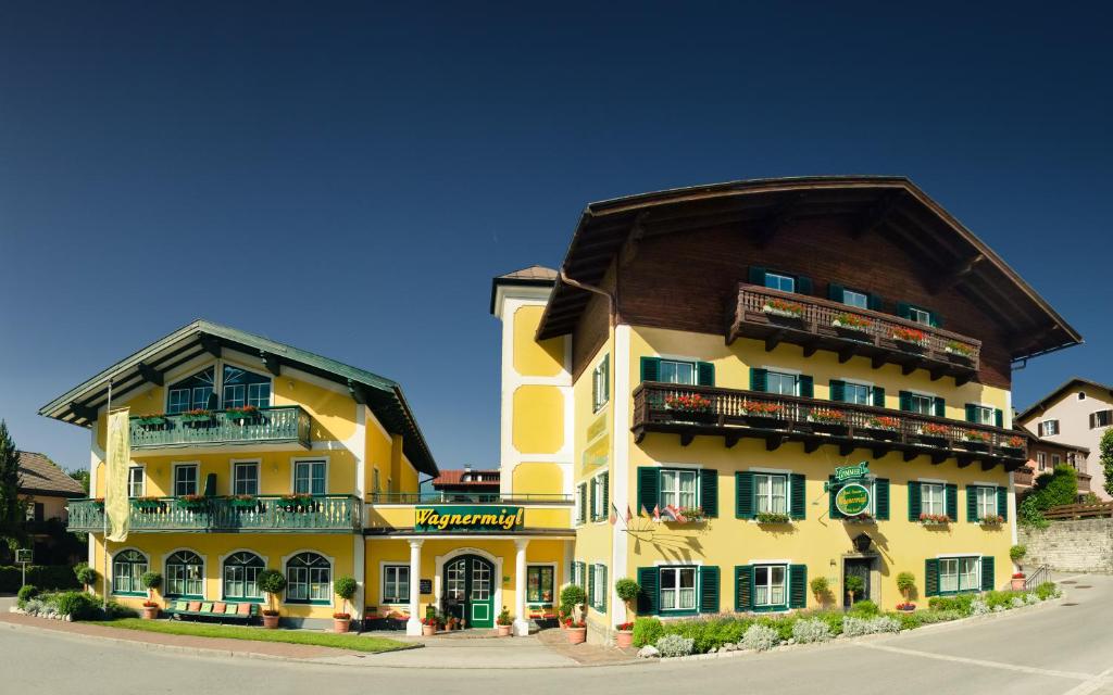 ein großes gelbes Gebäude mit einem Gammeldach in der Unterkunft Hotel-Pension Wagnermigl in Kuchl