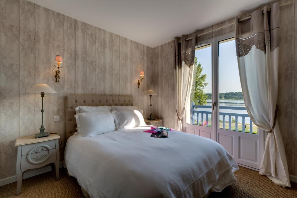 a bedroom with a bed and a large window at Les Eaux qui Rient in Sanguinet