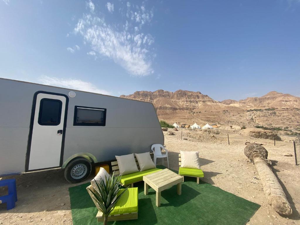 a caravan parked in the desert with chairs and tables at Ein Gedi caravan by Dory caravan in Ein Gedi