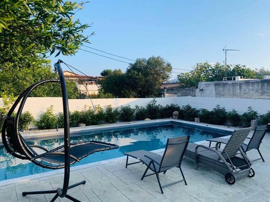 una piscina con un columpio y 2 sillas al lado en Astra House, en Porto Rafti