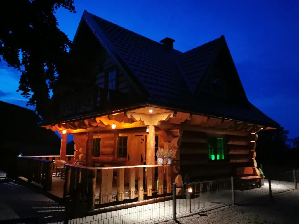 - une cabane en rondins la nuit avec des lumières sur la terrasse couverte dans l'établissement Vila Vilinka & Vila Native Vilinija resort Village, à Podčetrtek